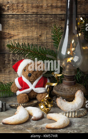 Christmas decoration with antique teddy bear in santa`s hat with burning vintage lamp and sugar cookies over wooden background Stock Photo
